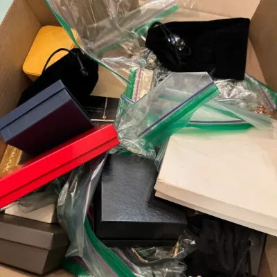 Sale Photo Thumbnail #13: Cardboard box filled with assorted jewelry boxes, velvet pouches, and plastic bags containing estate jewelry.