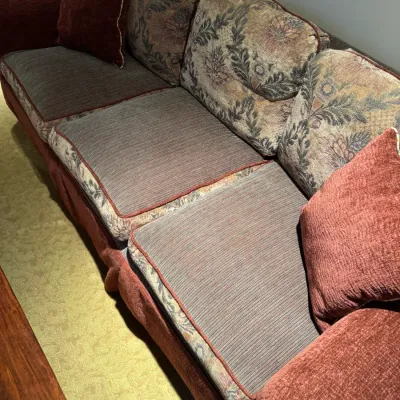 Sale Photo Thumbnail #71: Large three-cushion sofa featuring textured reddish-brown upholstery and tapestry floral-patterned back cushions, complete with matching accent pillows.