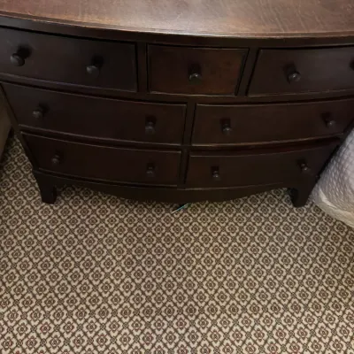 Sale Photo Thumbnail #64: Dark wood bowfront dresser featuring seven drawers with round wooden knobs, showing minor surface wear to the top finish.