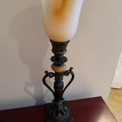 Sale Photo Thumbnail #67: Traditional buffet table lamp featuring an ornate dark metal column base with scrolling handles and a fluted amber-tinted frosted glass shade.
