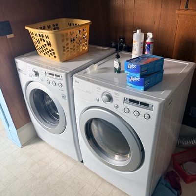 Matching white modern LG front-load washing machine and electric dryer set with digital displays.