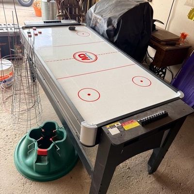 MD Sports air hockey table with manual bead scorers and plastic playing surface, shown in a garage setting alongside tomato cages and a...