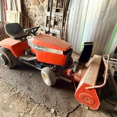 Vintage Simplicity lawn tractor fitted with a Snapper front-mounted snowblower attachment, showing signs of heavy outdoor use.