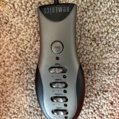 Handheld wired remote control for a HoMedics massage cushion or pad, featuring controls for heat and multi-zone massage functions.