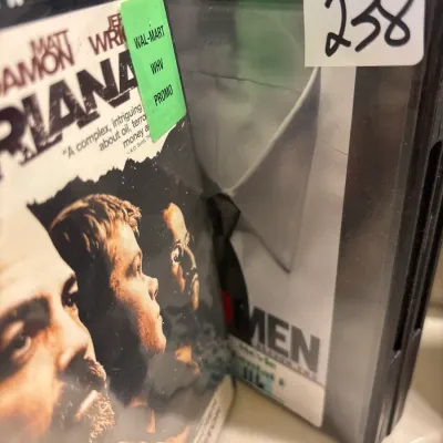 A collection of DVDs, including the movie Syriana and Mad Men Season Two Disc Four, housed in plastic cases.