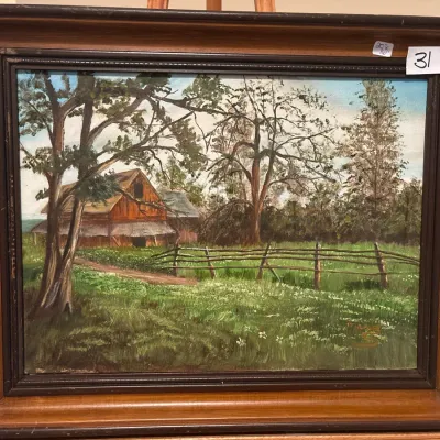 Framed oil painting depicting a rustic rural landscape with a red barn and split-rail fence, presented in a dark wood frame.