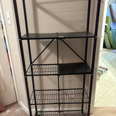 Tall black metal wire rolling baker's rack or shelving unit, featuring five tiers and caster wheels.
