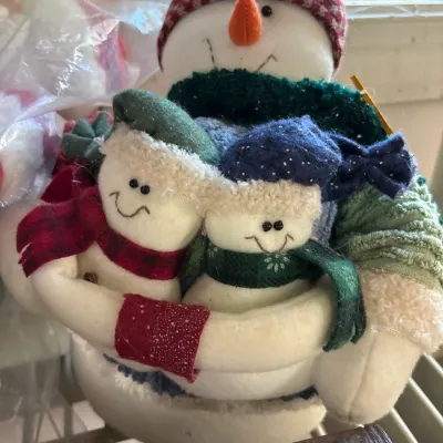 Plush snowman family decorative plush featuring a larger parent snowman hugging two smaller snowmen, dressed in knit hats and scarves.