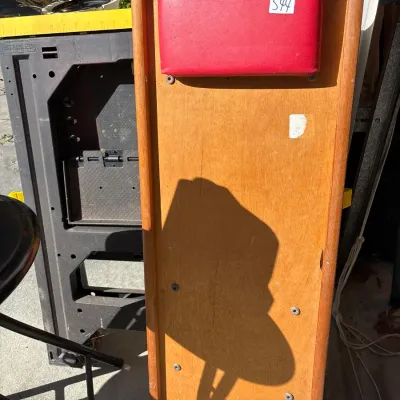 Vintage wooden slant board featuring a red vinyl headrest cushion and raised side edges.