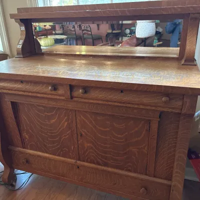 Antique tiger oak sideboard with an upper mirrored shelf, small top drawers, lower cabinet doors, and a bottom drawer.