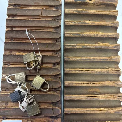Vintage wooden two-part cigar mold set showing heavy wear and age, accompanied by several small brass padlocks and keys.