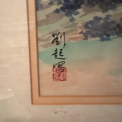 Detail of an East Asian watercolor painting featuring calligraphic signature and red artist seal mark, framed under glass.