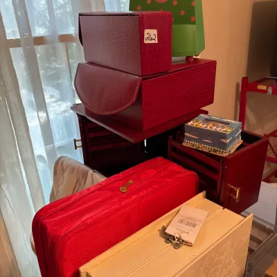 Collection of decorative storage boxes, including red faux-croc cases, a wooden jewelry chest, a red zippered organizer, and a Hallmark...