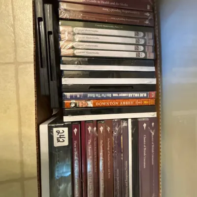 Cardboard box packed with various DVD box sets, including Great Courses educational series titles and Downton Abbey.