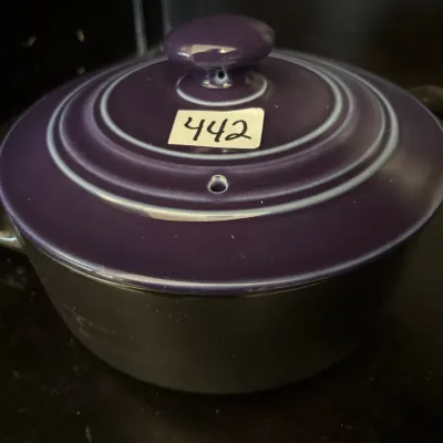 Le Creuset-style round Dutch oven featuring a dark purple enameled lid with a steam vent and a black base.