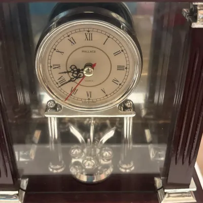 Wallace quartz anniversary clock housed in a wooden display case with glass panels and a silver-tone face featuring Roman numerals.