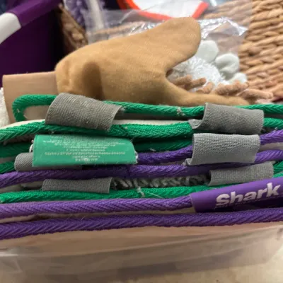 Stack of reusable Shark steam mop replacement pads stored in a plastic tub.