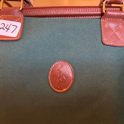 Vintage Polo Ralph Lauren green canvas duffel bag featuring brown leather trim and embossed pony logo patch.