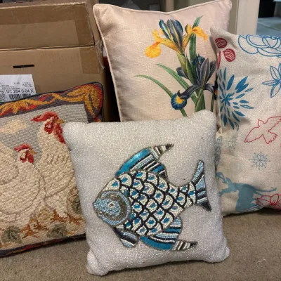 Collection of decorative throw pillows, including a beaded fish pillow, needlepoint rooster pillow, floral iris pillow, and printed linen...
