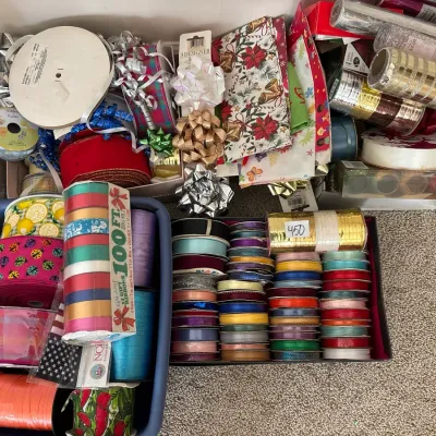 Large collection of gift wrapping supplies, featuring spools of decorative ribbon, gift bows, and rolls of wrapping paper.