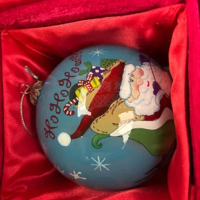 Hand-painted glass Santa Claus Christmas ornament nestled inside a red satin-lined display box.
