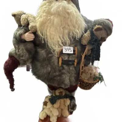 Handcrafted Father Christmas figure dressed in a grey faux-fur coat, adorned with miniature teddy bears and mounted on a wooden display...
