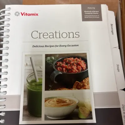 Vitamix "Creations: Delicious Recipes for Every Occasion" spiral-bound cookbook featuring indexed recipe sections.