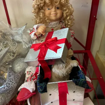 Vintage animated Christmas doll featuring a blonde girl holding a silver gift box with a red bow.