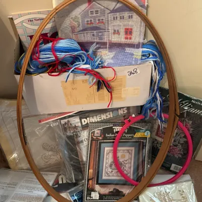 Collection of needlepoint and cross-stitch supplies, including embroidery hoops, yarn, needlepoint canvases, and packaged Dimensions and...