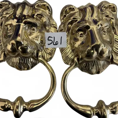 Pair of polished brass lion head door knockers with ring pulls, showing detailed mane work and shiny finish.
