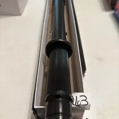 Black vintage flashlight baton resting inside its long cardboard packaging box.