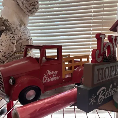 Festive Christmas decor collection featuring a red vintage-style metal pickup truck with "Merry Christmas" script, wooden...