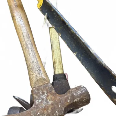 Assorted vintage hand tools, including two claw hammers with wood handles and a worn pry bar with yellow-painted ends.