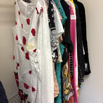 Closet rack filled with contemporary women's clothing, featuring dresses and tops in various colorful patterns and fabrics.