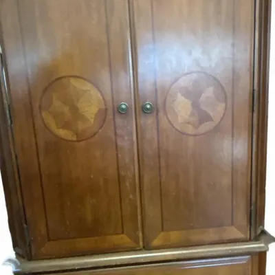 Traditional wooden armoire featuring inlaid geometric circular medallions on double upper doors over two lower drawers.