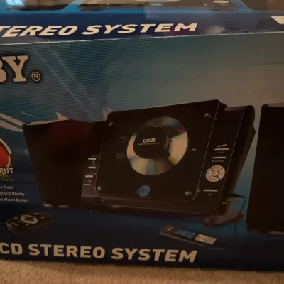 Coby CX-CD stereo system, new in original box, featuring an AM/FM tuner, digital backlit LCD display, and AUX input.
