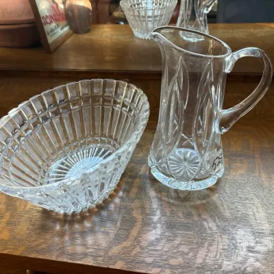 Pair of cut crystal glassware items, including an oval scalloped bowl and a small pitcher, both featuring geometric and ribbed designs.
