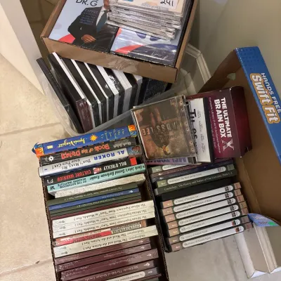 Large collection of CDs and DVDs in cardboard storage boxes, including music albums and Great Courses educational series.