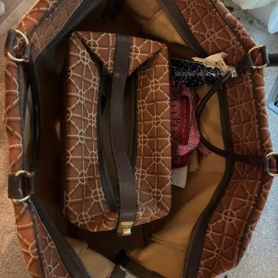 Vintage brown patterned tote bag containing a matching zippered pouch and small accessories, featuring dark leather straps and trim.