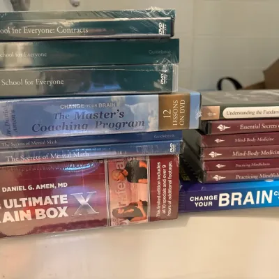 Assortment of educational and self-help DVD box sets and guidebooks, including titles from The Great Courses and Dr. Daniel Amen, mostly...