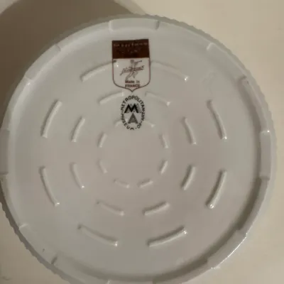 Underside of a white ceramic plate displaying a Metropolitan Museum of Art maker's mark and a label indicating it was made in France.
