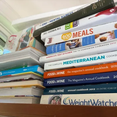 Stack of contemporary cookbooks and non-fiction books including Food & Wine annual collections, Weight Watchers, and America's...