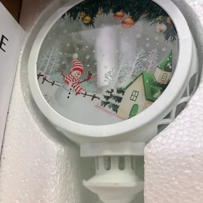 Decorative white Christmas street lamp head featuring a winter snow scene with a snowman and house, packed in original styrofoam.