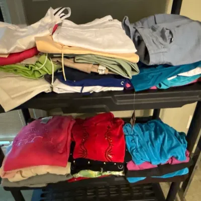 Folded colorful women's tops, pants, and shorts arranged on black plastic shelving units.