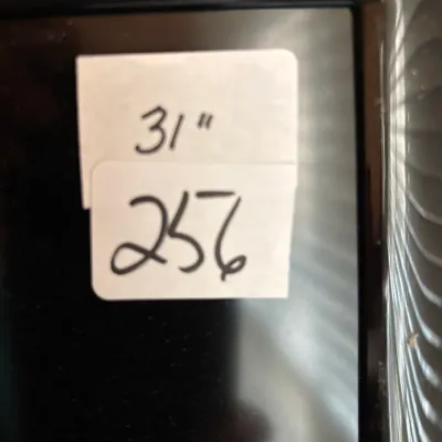 Close-up of a 31-inch television or monitor screen with handwritten sale tags attached to the top corner.