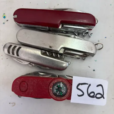 Collection of four vintage pocket knives, including multi-tool styles in red and silver casing, one featuring an integrated compass.