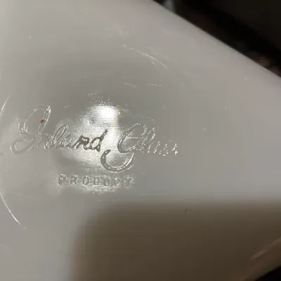 Close-up detail of a vintage white glass item showing an embossed 'Inland Glass Product' manufacturer mark.