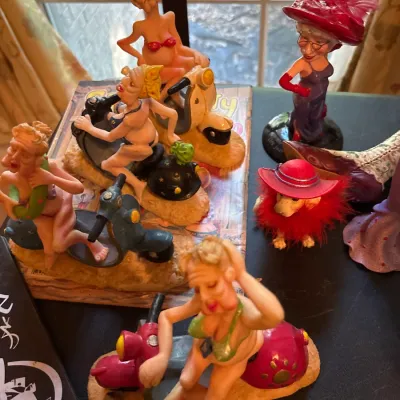 Collection of comical novelty resin figurines, featuring women in bikinis riding scooters and Red Hat Society themed characters.