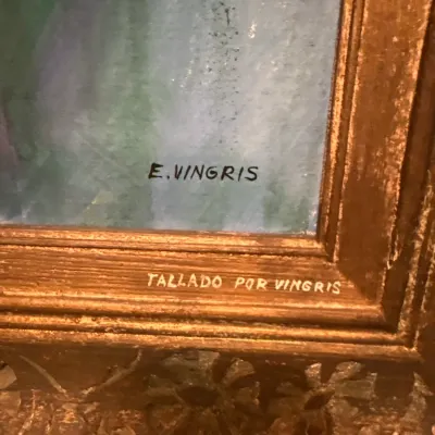 Close-up detail of a framed painting signed E. Vingris, with additional inscription reading 'Tallado Por Vingris' on the carved...