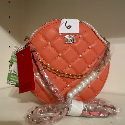 Coral pink quilted Badgley Mischka round crossbody bag featuring faux pearl accents, silver-tone logo hardware, and a chain strap.